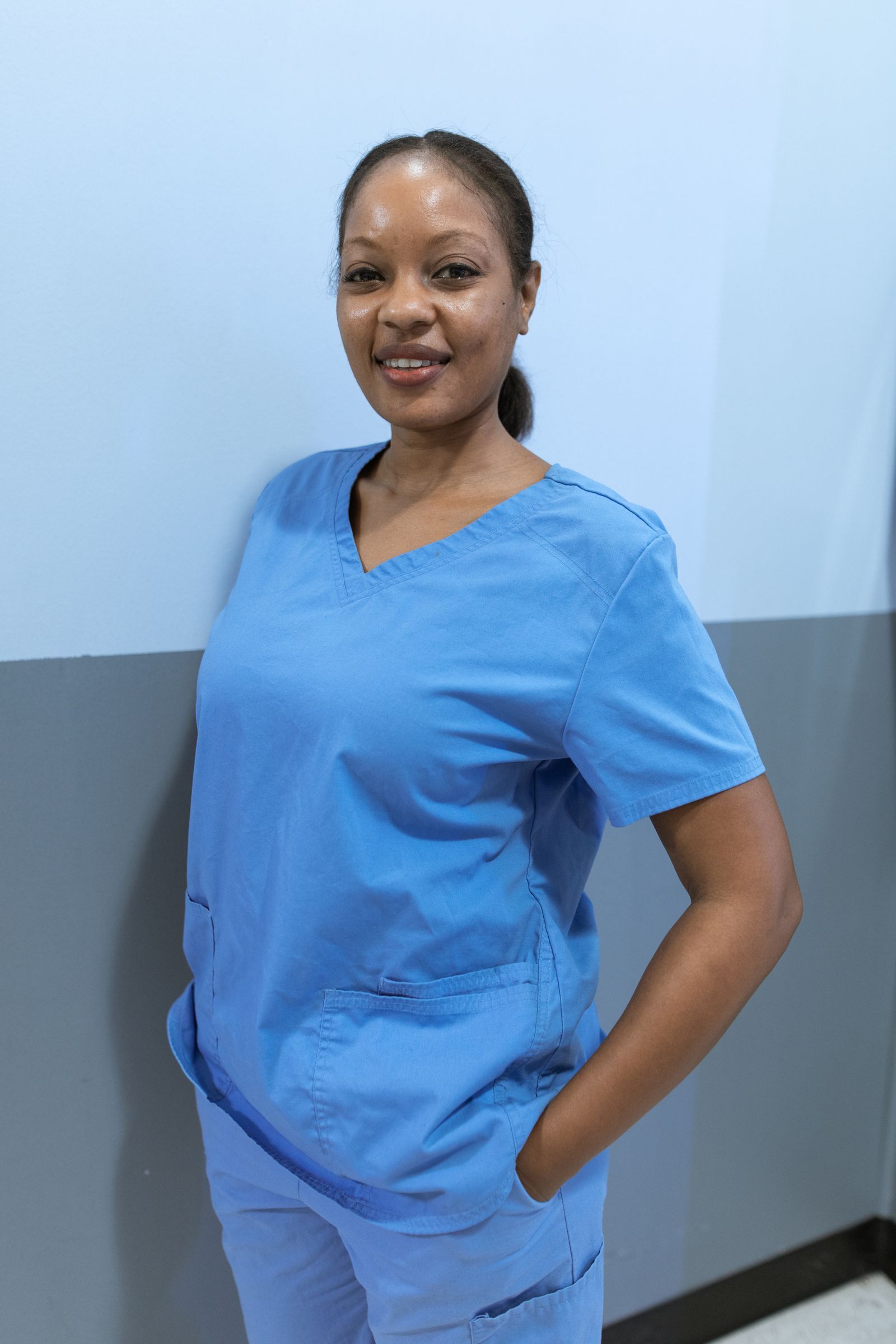 A HomeCare Roots pediatric nurse in scrubs smiling during a home visit.