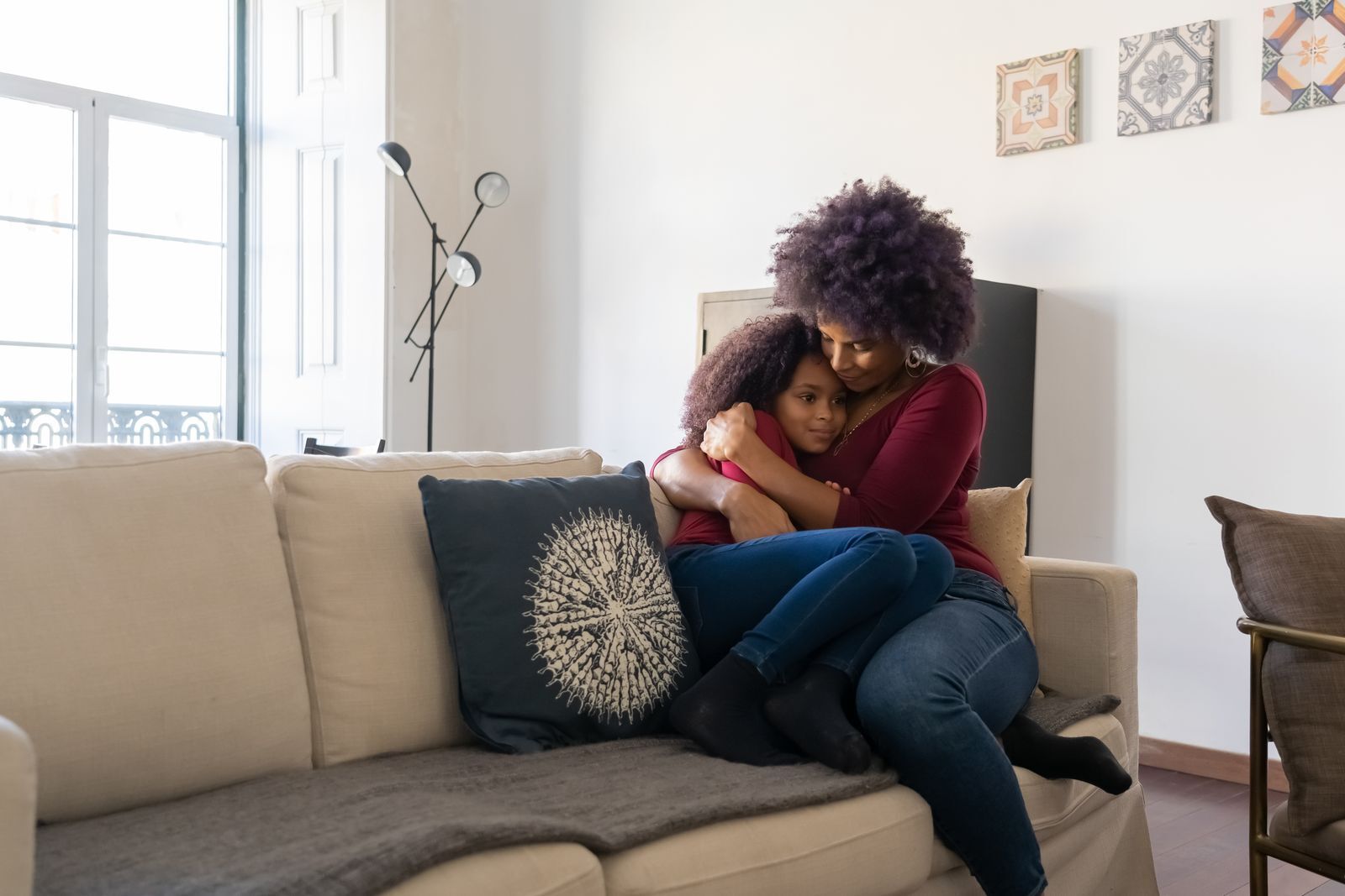 A HomeCare Roots pediatric nurse checking on a smiling young girl in her own living room.