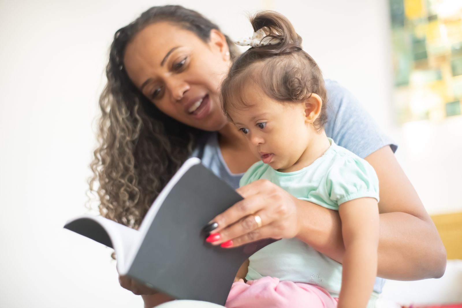 A HomeCare Roots caregiver playing with a young child on a sofa at home.